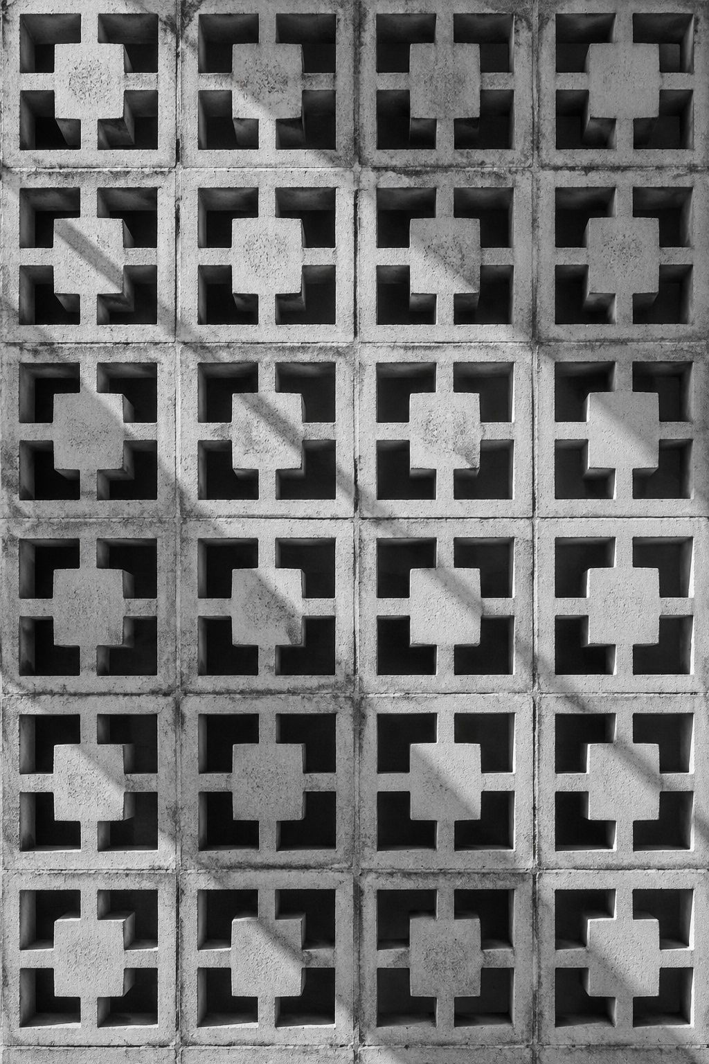 Black and white study of a concrete breeze-block wall and its sharp geometric shadows