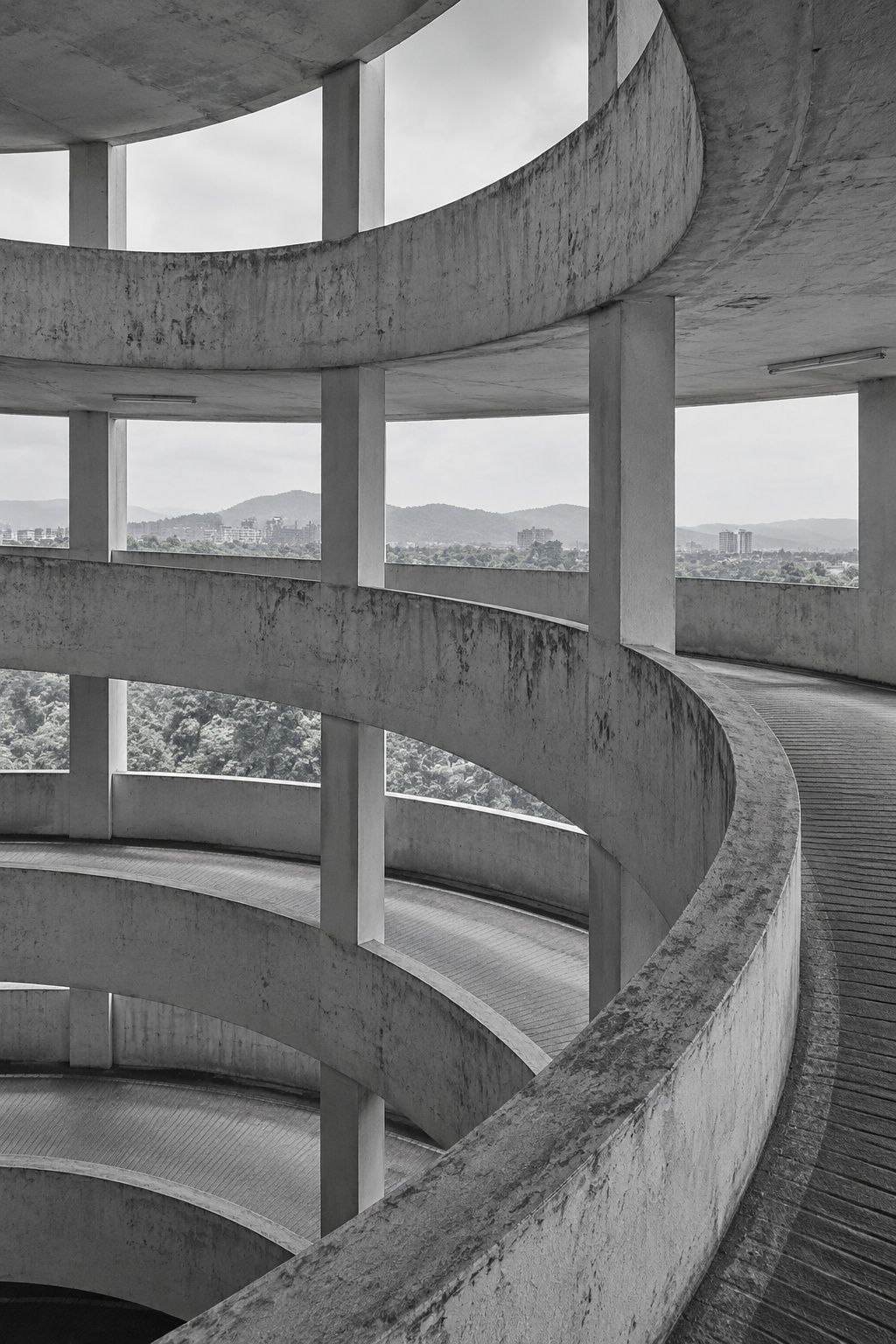 Black and white sweep of a concrete spiral ramp curving round in daylight